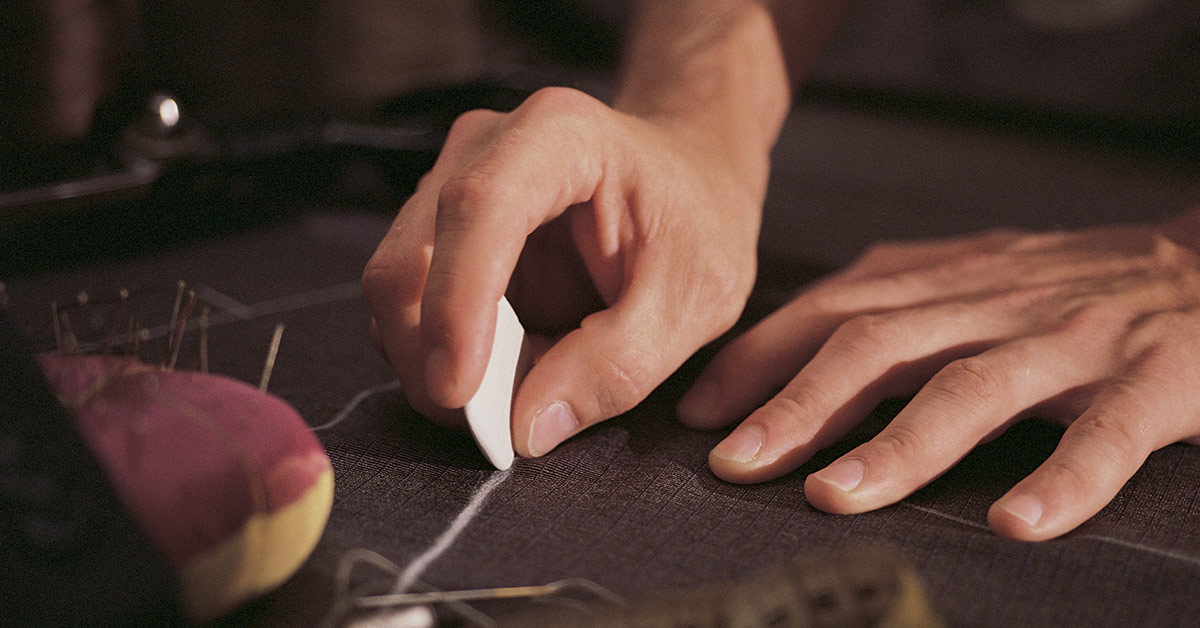 A tailor measure out cuts on a cloth