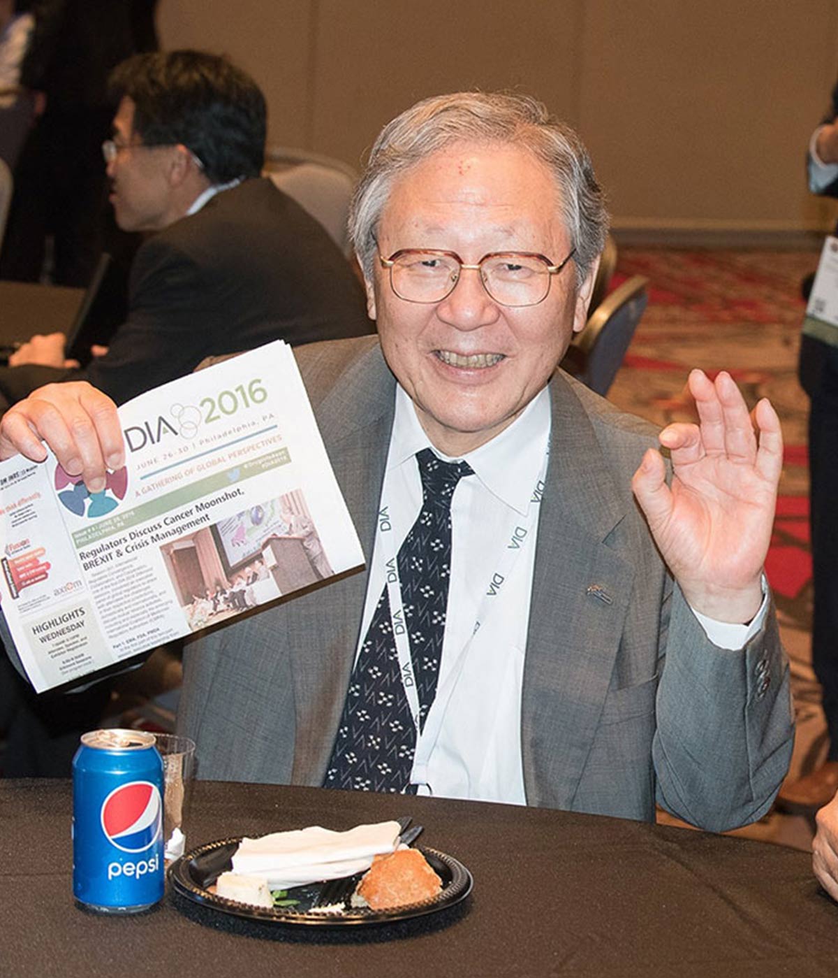 Dr. Tatsuya Kondo at the DIA Awards smiling and holding a DIA newsletter
